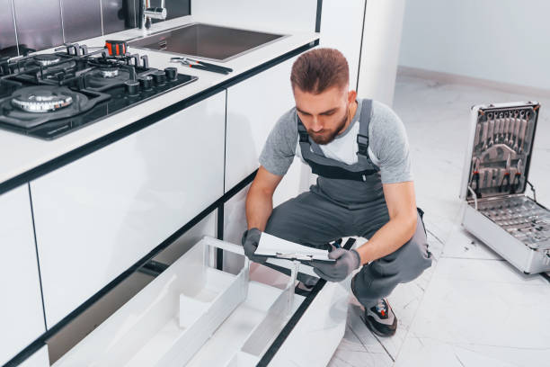 istock Young professional plumber in grey uniform working on the kitchen 1324872616