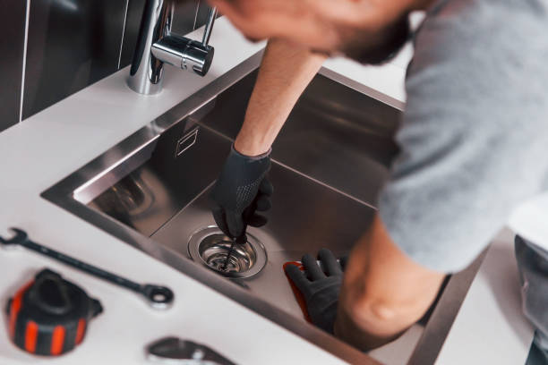 istock Young professional plumber in grey uniform working on the kitchen 1324872627