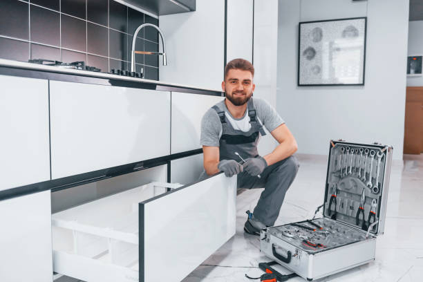 istock Young professional plumber in grey uniform using equipment on the kitchen and preparing for the work 1324872648