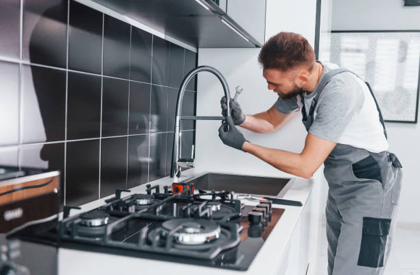 istock Young professional plumber in grey uniform fixing water tap on the kitchen 1324872699