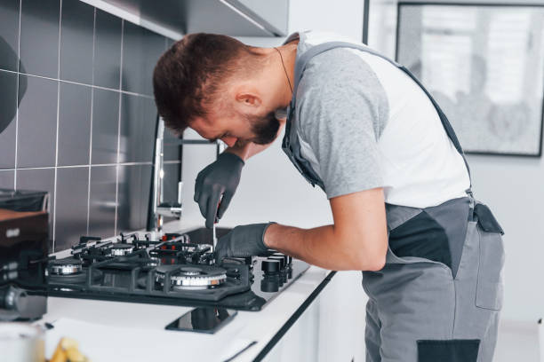 istock Young professional plumber in grey uniform working on the kitchen 1324872743