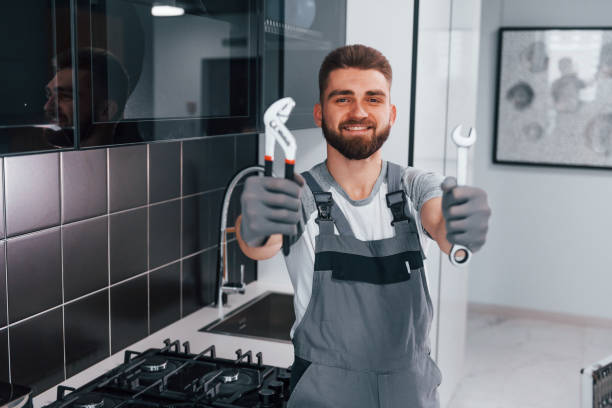 istock Young professional plumber in grey uniform standing on the kitchen and holding work equipment in hands 1324872758