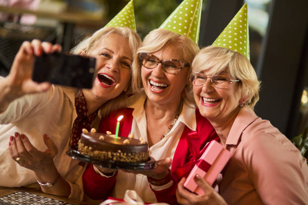 istock Senior ladies taking selfie while celebrating birthday in cafe 1324873699