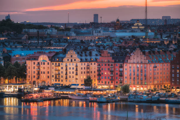 edificios iluminados por el río contra el cielo al atardecer - kungsholmen fotografías e imágenes de stock