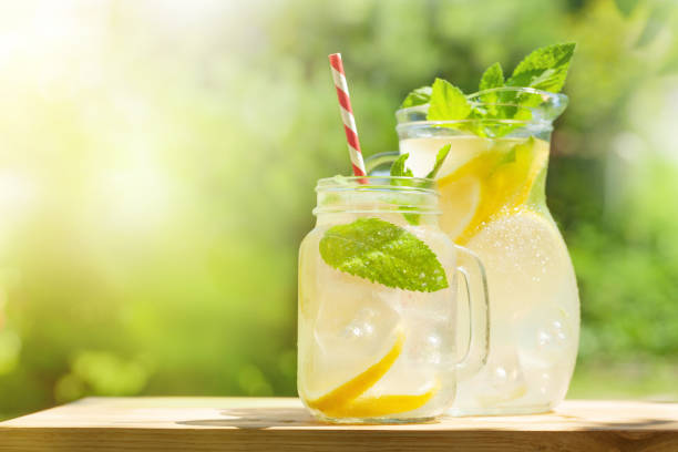 Fresh homemade lemonade with lemon and mint Fresh homemade lemonade with lemon and mint. Outdoor garden table on sunny day. With copy space lemon soda photos stock pictures, royalty-free photos & images