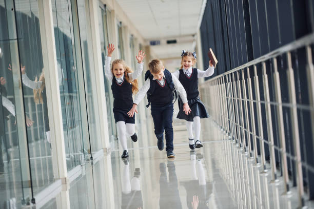 istock Active school kids in uniform running together in corridor. Conception of education 1324879272