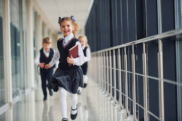 aktywne dzieci w szkole w mundurkach biegają razem po korytarzu. koncepcja edukacji - elementary student school uniform uniform education zdjęcia i obrazy z banku zdjęć