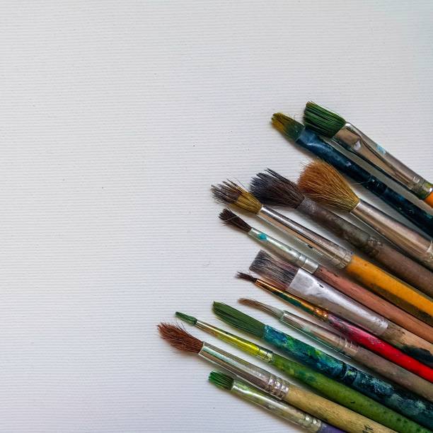 istock Top view of a blank canvas, old and different paint brushes. Space for text 1324883001
