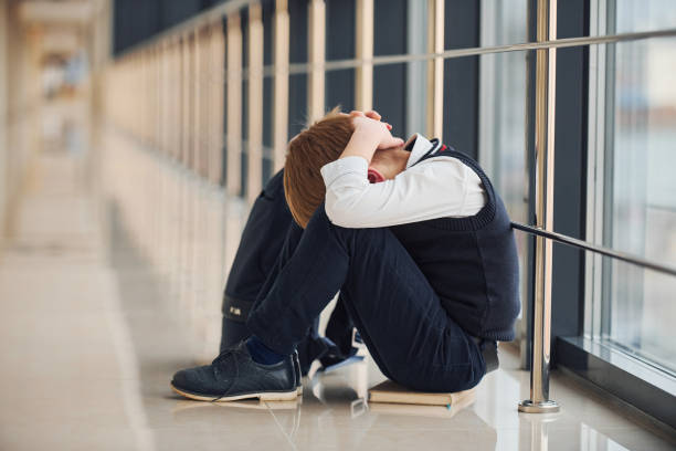 istock Boy in uniform sitting alone with feeling sad at school. Conception of harassment 1324883908
