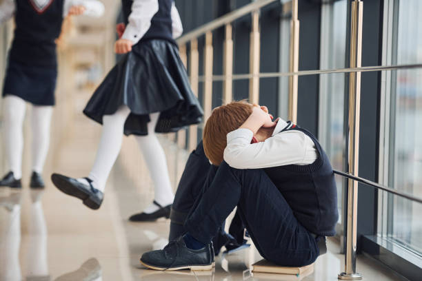 istock Boy in uniform sitting alone with feeling sad at school. Conception of harassment 1324883942