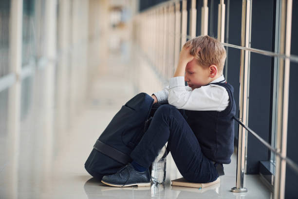 istock Boy in uniform sitting alone with feeling sad at school. Conception of harassment 1324883994