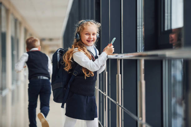 ein kleiner schuljunge stiehlt einem mädchen dinge aus der tasche, während sie musik hört - bullying child teasing little boys stock-fotos und bilder