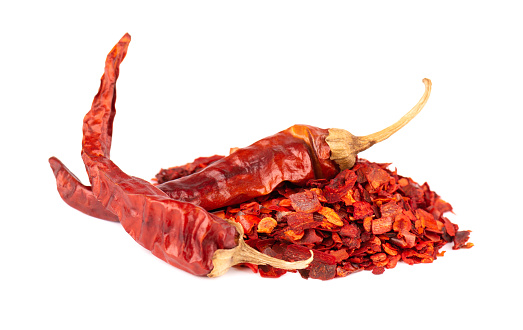 Dried red chili flakes with seeds, isolated on white background. Chopped chilli cayenne pepper. Spices and herbs