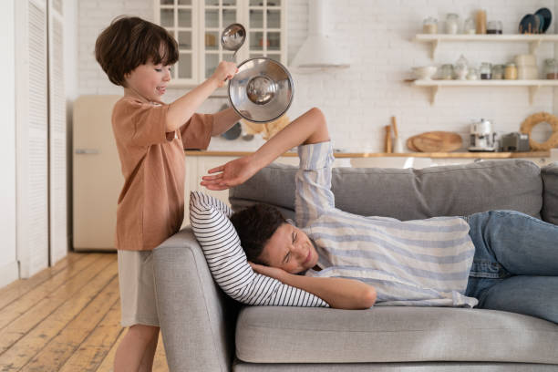 criança roncando utensílios de cozinha como mãe estressada e cansada dormindo no sofá na sala de estar - rumbling - fotografias e filmes do acervo