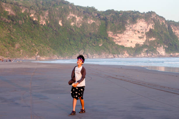 Indonesian Teenage Boy walking on the Parangtritis beach, Yogyakarta