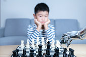 Smart boy playing chess with AI robot