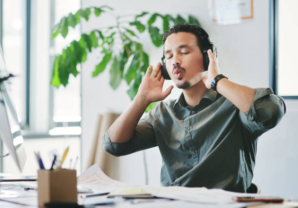 Shot of a young businessman listening to music in an office Listening to some good music to start the day whistling stock pictures, royalty-free photos & images