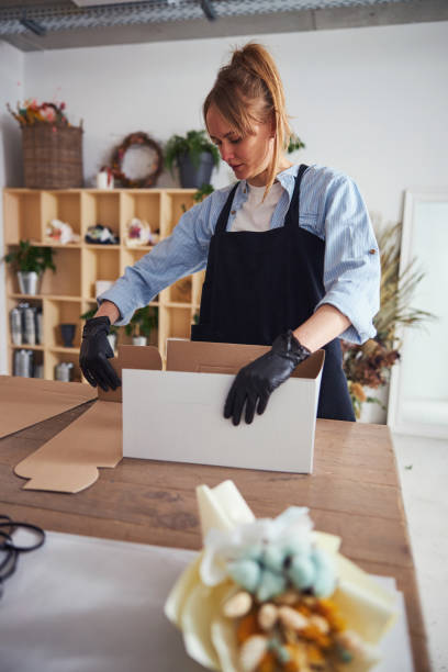istock Young florist putting together a cardboard box 1324889574