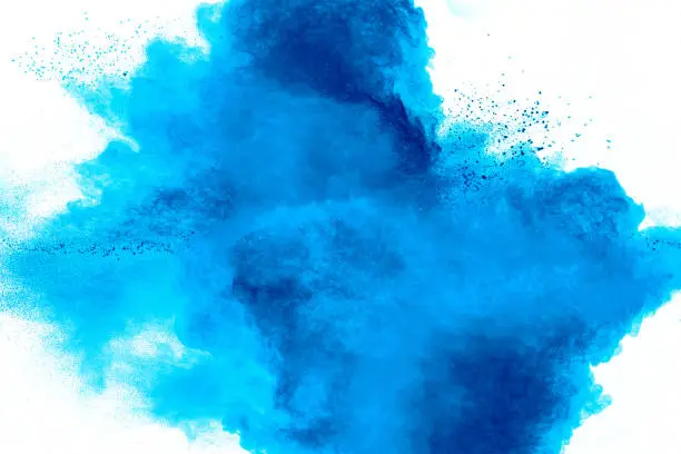 Photo of Bizarre forms of blue powder explode cloud on white background. Launched blue dust particles splashing.