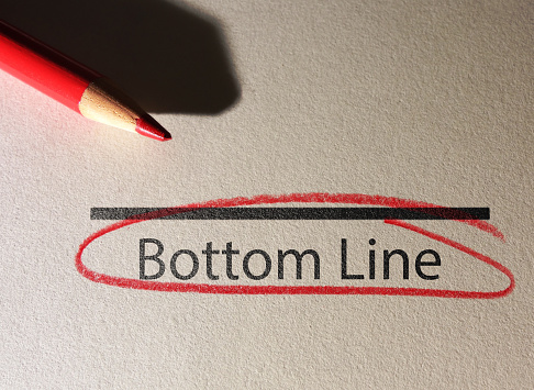 Bottom Line text circled in red pencil on textured paper surface