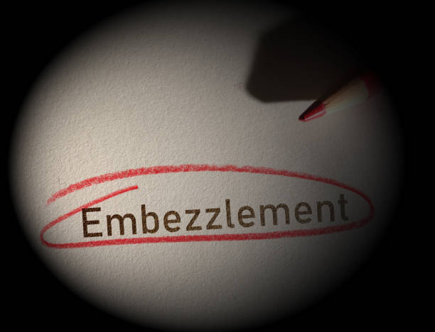 Embezzlement text circled in red pencil on dark background stock photo