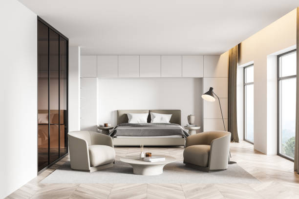 istock White bedroom interior with armchairs and bed on parquet floor with windows 1324892057