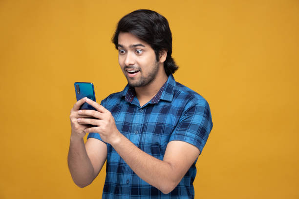 young man using mobile phone isolated over yellow background:- stock photo stock photo