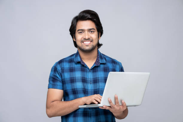 istock young man using laptop on gray background:- stock photo 1324893078