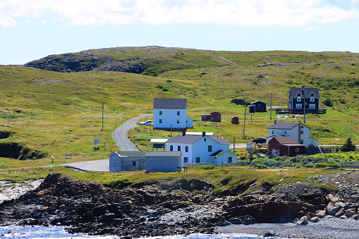 Traditional saltbox houses on the coast, Elliston, Newfoundland. Beach and coastline in foreground.