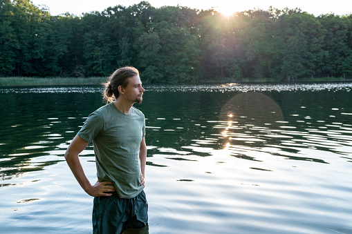 Summer portrait: young man by the lake looking into distance
