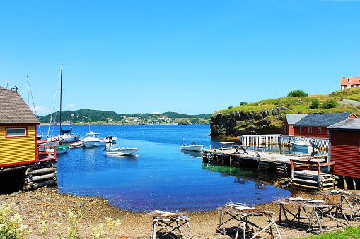 Fishing village, harbor scene; fish drying on stages, boats moored to the pier, Trinity, Newfoundland Labrador.