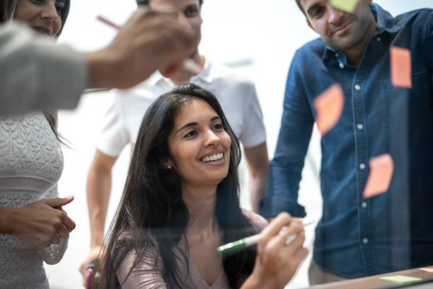 istock Coworkers doing a brainstorm using adhesive notes on a glass in the office 1324893592