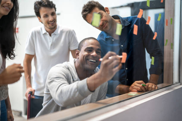 istock Coworkers doing a brainstorm using adhesive notes on a glass in the office 1324893594