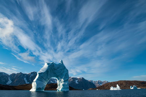 istock A towering, arched iceberg stands or floats in a protected bay on a sunny, partly cloudy day 1324894606
