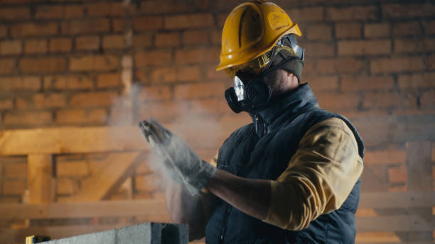 Male builder cleaning nose during work Man shaking off dust from gloves then removing respirator and cleaning nose from dirt during work on construction site real time stock pictures, royalty-free photos & images