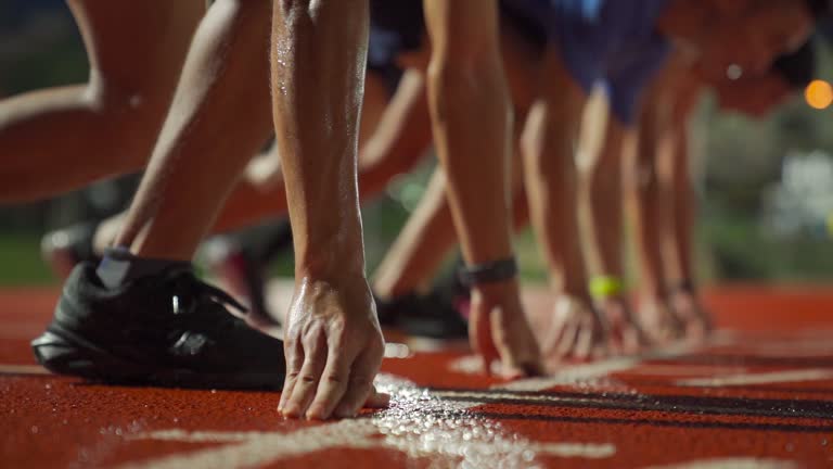 slow motion asian chinese male athletes lining up getting ready starting line running at men's track rainy late evening in stadium