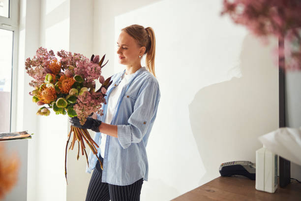 istock Smiling floral arranger admiring a spring bouquet in her hands 1324895989