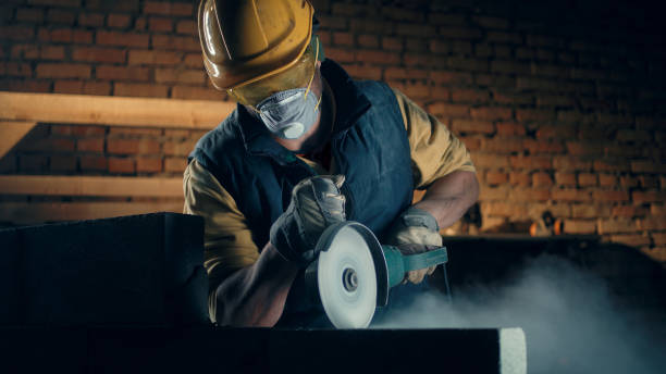 Male builder in respirator using angle grinder Man in hardhat and respirator cutting concrete wall with angle grinder while working on construction site real time stock pictures, royalty-free photos & images