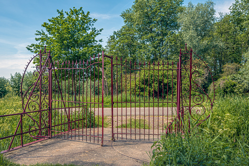 Old and restored wrought iron gate of a now disappeared Dutch estate. The fence is painted in a dark red color.