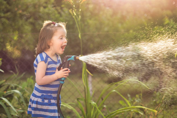 istock Excited girl watering flower 1324898184