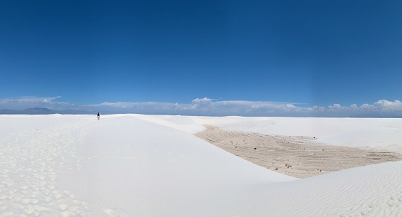 White Sands NP, New Mexico, USA - May 31, 2021: Female tourist is walking on sand dune in White Sands National Park in New Mexico, USA.