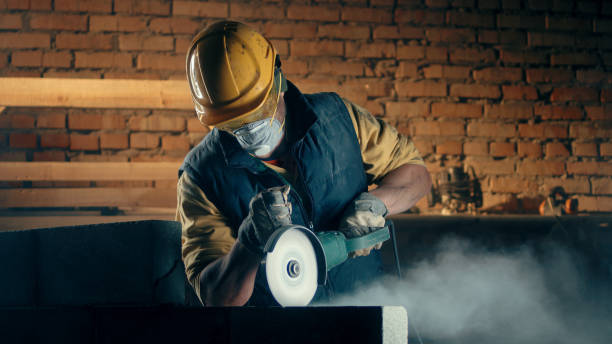 Male builder in respirator cutting wall Man in hardhat and respirator using angle grinder on concrete wall while working on construction site real time stock pictures, royalty-free photos & images