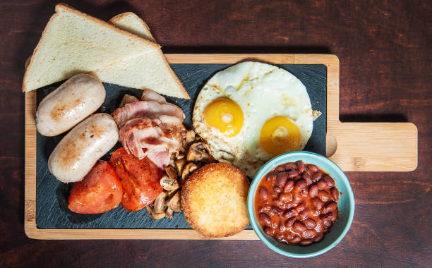 istock Fried eggs with bacon, sausages and tomatoes. Top view 1324902227