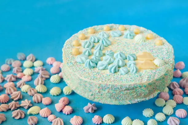 blue cake with candies for babyshower party with meringue. Homemade cake for a newborn boy On a blue background.