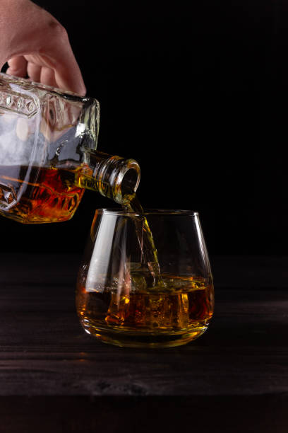 istock A hand pours brandy from a decanter into a glass. Alcoholic beverages, dark background. Vertical orientation. 1324902927