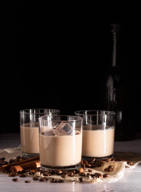 copos com licor de creme e gelo. grãos de café, garrafa preta no fundo. - cream liqueur - fotografias e filmes do acervo