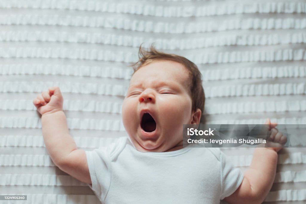 Infant baby sleeping and yawning on white sheets Infant baby sleeping and yawning on white sheets at home Baby - Human Age Stock Photo