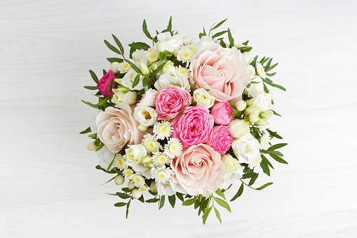 Bouquet of different flowers on white wooden table. Top view.