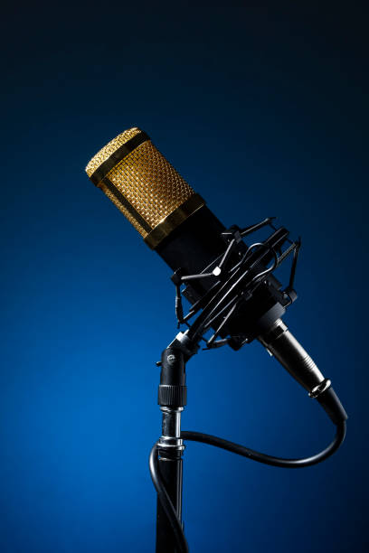 istock Base-mounted, corded professional desktop microphone with a blue background. 1324908226