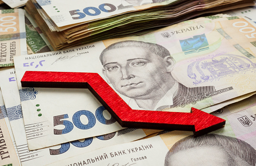 Financial crisis and inflation in Ukraine. Ukrainian money hryvnia and down arrow.